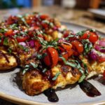 Close-up of grilled Bruschetta chicken topped with fresh tomatoes, red onion, basil, and balsamic glaze.