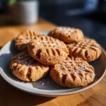 A close-up of several Easy Peanut Butter Cookies sprinkled with sea salt on a grey plate.