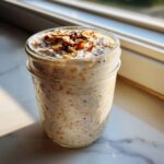 Close-up of high protein overnight oats in a mason jar, topped with nuts and seeds.