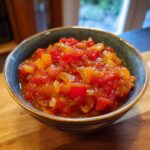 Close-up of a bowl filled with vibrant, chunky homemade salsa made with tomatoes, onions, and peppers.
