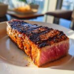 Close-up of a perfectly cooked tuna steak with a flavorful marinade, showcasing its tender pink interior.