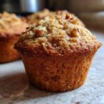 Close-up of a moist banana nut muffin with visible nuts on top.