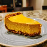 A delicious slice of no bake pumpkin cheesecake with a graham cracker crust on a blue plate.