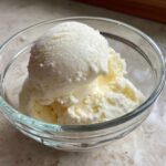Two scoops of creamy protein ice cream in a clear glass bowl.