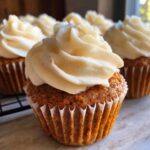 Close-up of a tall, domed pumpkin spice cupcake topped with swirls of creamy frosting.