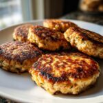 A close-up shot of several golden brown tuna patties, perfectly cooked and arranged on a white plate.