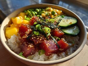 A vibrant Tuna Poke Bowl featuring marinated tuna cubes, rice, mango, edamame, cucumber, and seaweed.