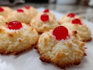 Close-up of delicious whipped shortbread cookies topped with bright red cherries.