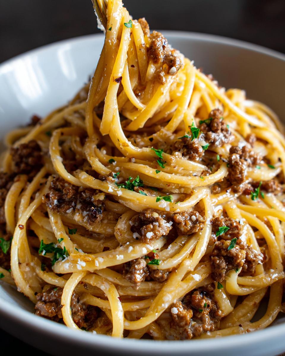 A fork twirling a generous portion of Beef and Garlic Butter Linguine, showing the rich sauce and minced beef.