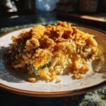 A close-up of a serving of chicken broccoli rice casserole with a crispy, golden-brown topping.