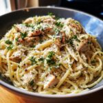 A close-up of a bowl of Chicken Garlic Parmesan Pasta, featuring spaghetti, grilled chicken pieces, and grated parmesan cheese.