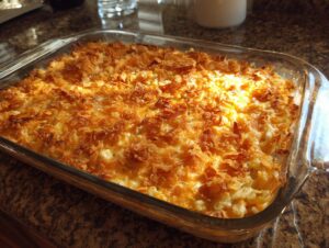A golden brown chicken hashbrown casserole baked in a clear glass dish, topped with crispy fried onions.