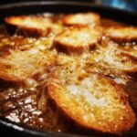 Close-up of bubbling crockpot French onion soup topped with toasted bread and melted cheese.