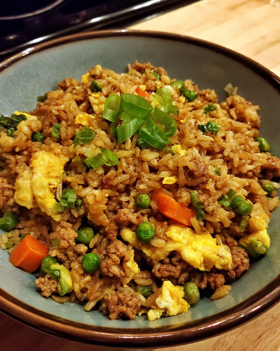 A close-up of delicious ground chicken fried rice in a blue bowl, garnished with green onions.