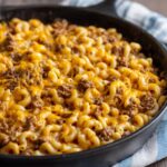 Close-up of cheesy Homemade Hamburger Helper with elbow macaroni and ground beef in a cast iron skillet.