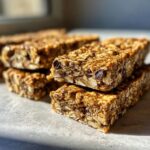 Close-up of a stack of homemade protein bars, showing oats, seeds, and raisins.