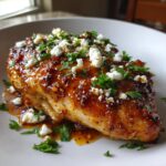 A juicy chicken breast coated in a glossy hot honey glaze, topped with crumbled feta cheese and fresh parsley.
