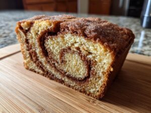 A close-up of a slice of perfect Amish cinnamon bread, showing the swirled cinnamon filling and golden crust.