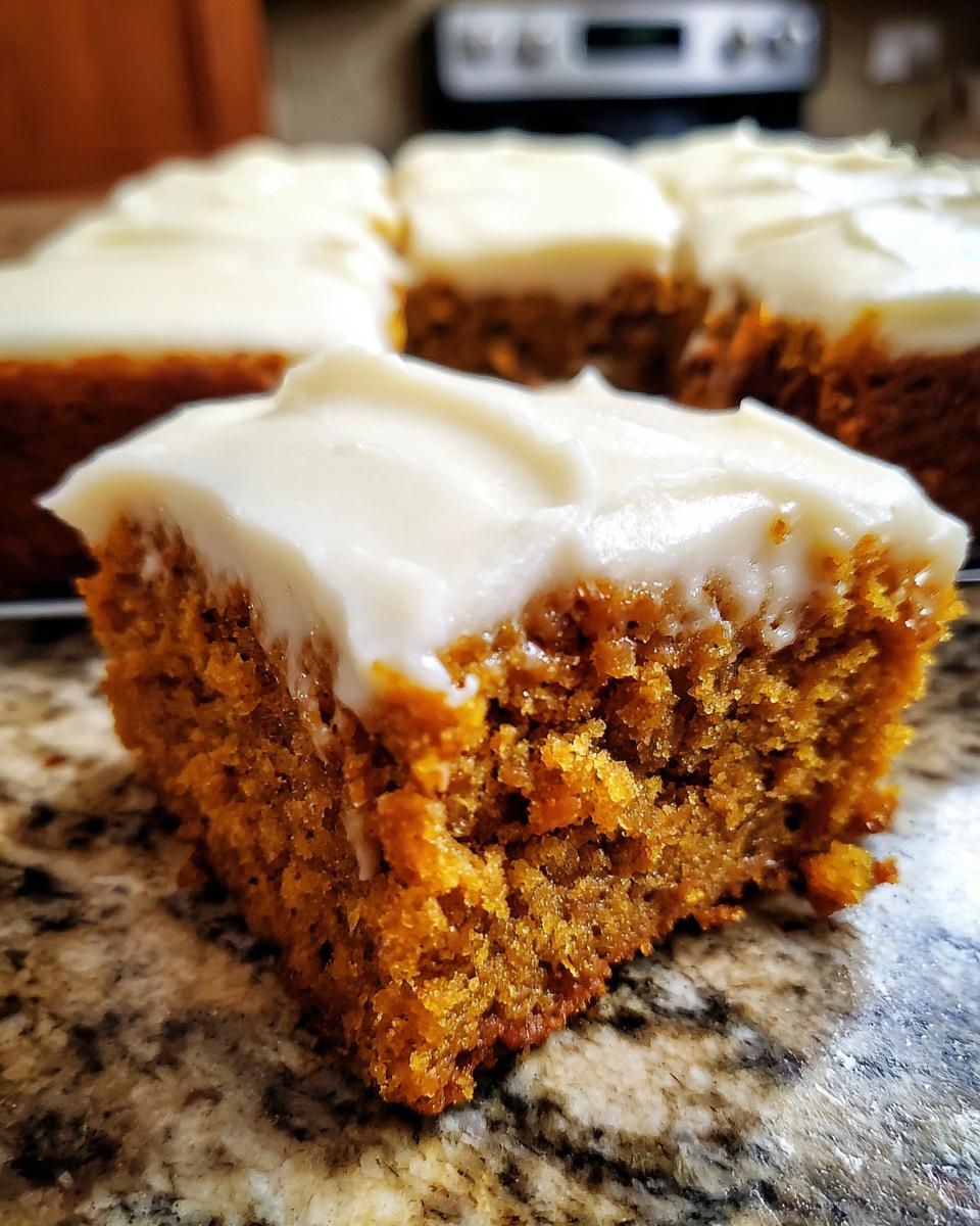 Close-up of a moist pumpkin bar topped with thick, creamy frosting.