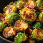 Close-up of perfectly roasted Brussels sprouts with crispy bacon pieces mixed in.