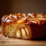 Close-up of a slice of sourdough apple fritter focaccia, showcasing tender apple slices and a glistening glaze.