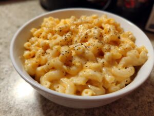 A bowl of creamy stovetop mac and cheese, seasoned with black pepper.
