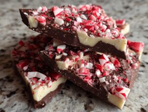 Close-up of stacked slices of dark and white chocolate peppermint bark topped with crushed candy canes.