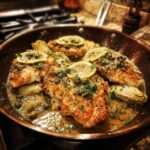 Golden brown Artichoke Chicken Piccata pieces topped with lemon slices and capers in a copper skillet.