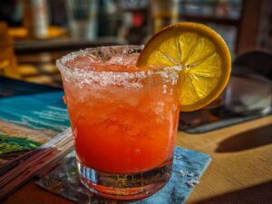 A vibrant Blood Orange Margarita cocktail in a salt-rimmed glass, garnished with an orange slice and filled with ice.