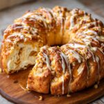 A delicious Caramel Apple Cream Cheese Crescent Ring drizzled with caramel and icing, topped with nuts.