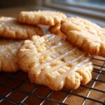 Close-up of cardamom shortbread cookies drizzled with a light glaze and sprinkled with zest.
