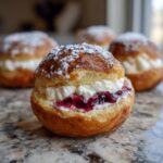Close-up of a delicious cheesecake stuffed doughnut filled with cream and berry jam, dusted with powdered sugar.