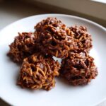 A small pile of rich, chocolate-coated haystack cookies resting on a white plate.