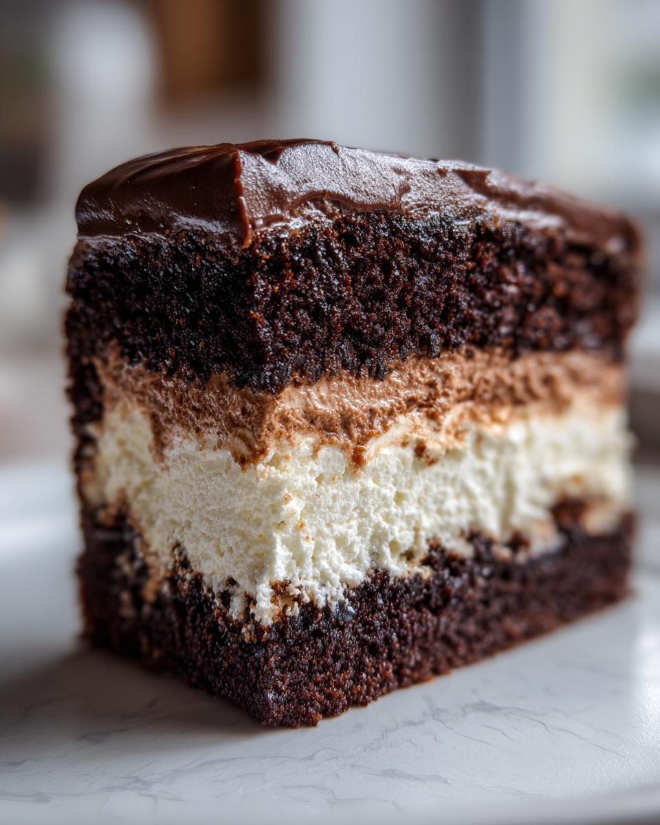 A close-up slice of a multi-layered chocolate Italian Love Cake featuring dark cake, white cream, and chocolate mousse.