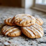 A stack of freshly baked cinnamon bun cookies drizzled with white glaze and sprinkled with sugar.