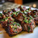 Close-up of juicy Cowboy Butter Steak Bites topped with fresh herbs and garlic.