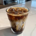 A close-up of a New Orleans Crème Brûlée Iced Coffee with swirls of cream and ice.