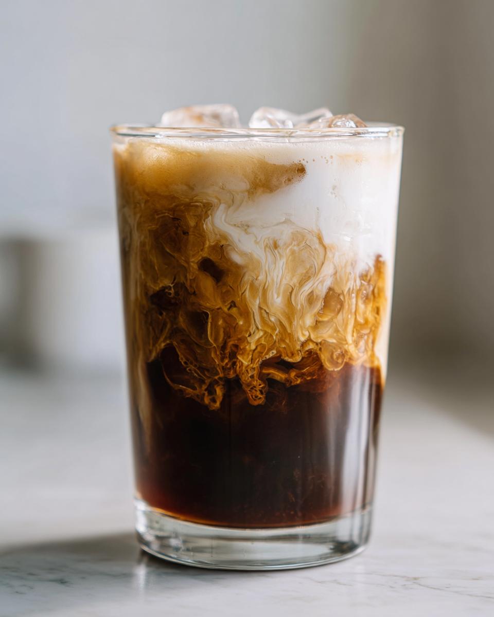 Close-up of a New Orleans style crème brûlée iced coffee with swirling cream and ice.