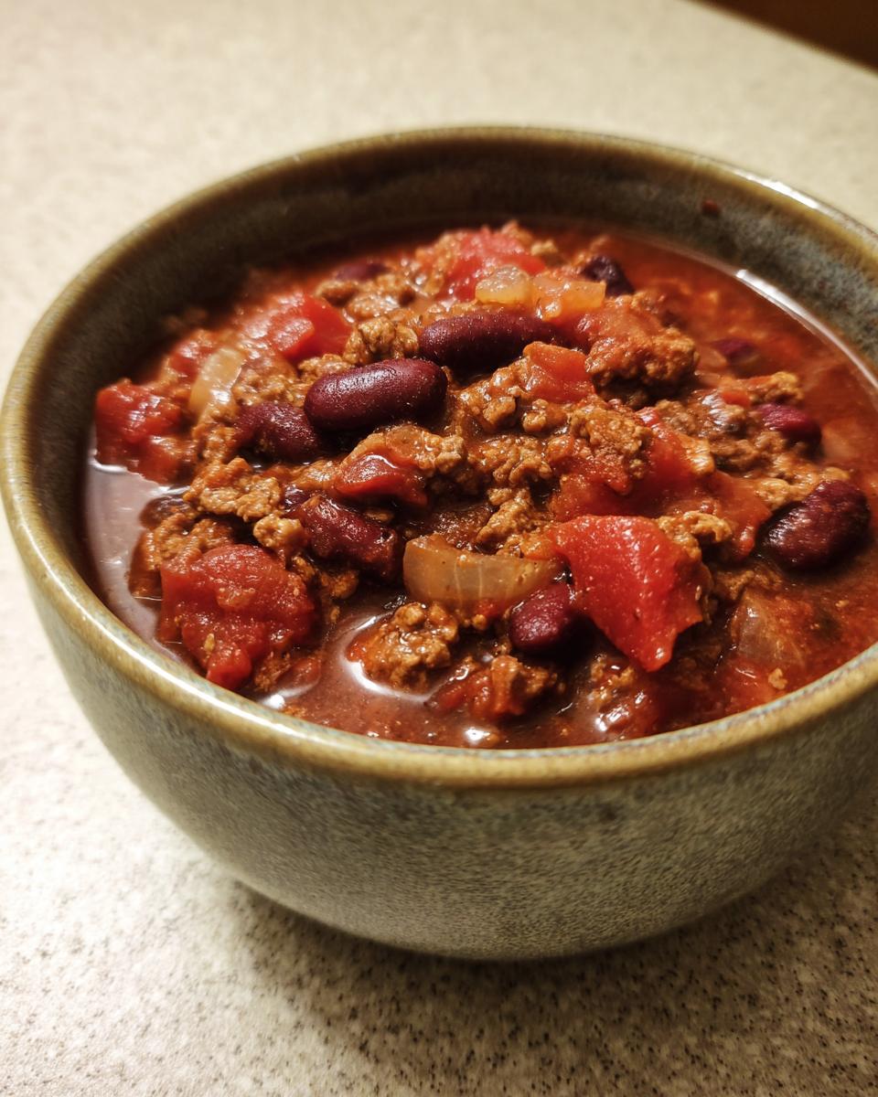 A close-up of a bowl filled with delicious crock pot chili, featuring ground beef, kidney beans, and tomatoes.