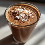 A refreshing Dark Chocolate Coffee Smoothie topped with shredded coconut and chocolate shavings.