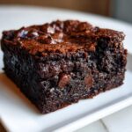 A close-up, tempting shot of a single, fudgy square of sweet potato brownies with visible chocolate chips.