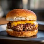 Close-up of a perfectly cooked juicy burger with melted cheddar cheese on a toasted bun.