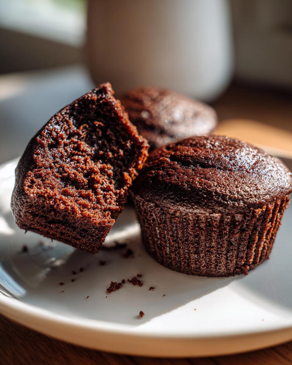 Close-up of a moist chocolate cupcake, with one cupcake broken in half to reveal its fluffy interior.