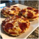 Three freshly baked pepperoni english muffin pizza halves topped with melted, bubbly cheese.