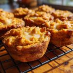 Close-up of freshly baked pumpkin pie cookies with a creamy center on a black cooling rack.