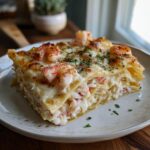 A decadent slice of shrimp and crab lasagna, topped with cooked shrimp and fresh parsley.