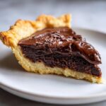 Close-up of a rich slice of hot fudge pie showing a dark chocolate filling and flaky crust.