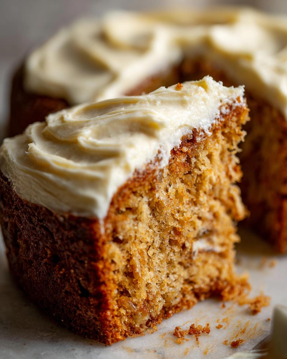 Close-up of a slice of moist sourdough banana cake with creamy white frosting.