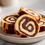Close-up of sliced pinwheel cookies showing a perfect chocolate and vanilla swirl pattern on a speckled plate.