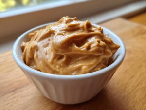 Close-up of thick, creamy peanut sauce filling a small white bowl, ready for serving.